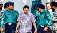 Police personnel escort detainees Chowdhury Abdullah Al-Mamun (C), a former police inspector general and Ziaul Ahsan (back 2R), a former military general and former director general of the National Telecommunication Monitoring Centre (NTMC), to Bangladesh's International Crimes Tribunal (ICT) court in Dhaka on November 20, 2024. Photo by Munir UZ ZAMAN / AFP.