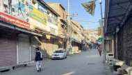 Men walk past a market closed by traders during a strike against sectarian attacks in Kurram district. (Photo by Dilawer Khan / AFP)