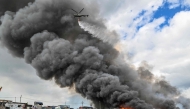 A Philippine Air Force helicopter drops water over houses on fire at Tondo in Manila on November 24, 2024. (Photo by Jam Sta Rosa / AFP)