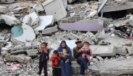 A Palestinian family rests on the rubble of a building west of Gaza City, on November 25, 2024. (Photo by Omar Al-Qattaa / AFP)