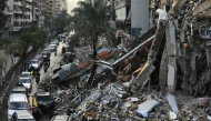 Motorists drive past a destroyed building in Beirut's southern suburbs on November 27, 2024, after a ceasefire took effect. (Photo by AFP)
 