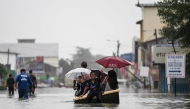 People use a boat through a flooded street during heavy rain in Pasir Puteh, in Malaysia's Kelantan state on November 30, 2024. (Photo by Mohd Rasfan / AFP)