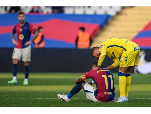 Barcelona's Brazilian forward #11 Raphinha (C) is consoled by Las Palmas' Spanish midfielder #11 Benito Ramirez (R) after their Spanish league football match between FC Barcelona and UD Las Palmas at the Estadi Olimpic Lluis Companys in Barcelona on November 30, 2024. (Photo by Josep LAGO / AFP)
