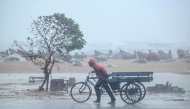 A man pulls his three-wheeler cart amid heavy wind and rainfall at the Marina Beach in Chennai on November 30, 2024, ahead of the landfall of cyclone Fengal in India's state of Tamil Nadu. Photo by R.Satish BABU / AFP