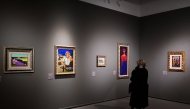 A woman looks at paintings during a press preview of the exhibition titled 