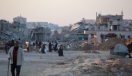 Palestinians walk in a devastated neighbourhood due to Israeli strikes in the southern Gaza Strip's city of Khan Yunis on December 2, 2024. Photo by Bashar TALEB / AFP.