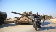 Anti-government fighters move past abandoned Syrian army military equipment and vehicles, as they reach al-Safirah town southeast of Syria's Aleppo city on December 3, 2024. Photo by Aref TAMMAWI / AFP.