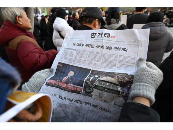 Photo used for representational purposes. A man reads an extra edition newspaper in downtown Seoul on December 4, 2024, after martial law was lifted. Photo by Jung Yeon-je / AFP.