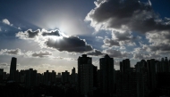 (Files) This file photo taken on September 17, 2024 shows buildings silhouetted as clouds drift past the sun in Shanghai. (Photo by Hector Retamal / AFP)