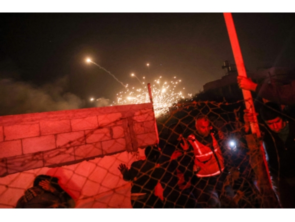 People run for cover as an explosion from an Israeli strike occurs near a makeshift camp for displaced Palestinians, in Mawasi Khan Yunis in the southern Gaza Strip on December 4, 2024. (Photo by Bashar Taleb / AFP)