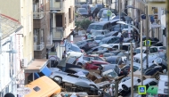 File: Pedestrians stand next to piled up cars following deadly floods in Sedavi, south of Valencia, eastern Spain, on October 30, 2024. (Photo by Jose Jordan / AFP)