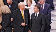 French President Emmanuel Macron (R) and US President-elect Donald Trump (C) speak ahead of a ceremony to mark the re-opening of the landmark Notre-Dame Cathedral, in central Paris, on December 7, 2024. (Photo by Ludovic Marin / Pool / AFP)