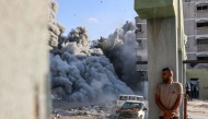 File: A man takes cover behind a column as an explosion propagates smoke and dust during an Israeli strike which reportedly targeted a school in the Zeitoun district on the outskirts of Gaza City, on September 1, 2024. (Photo by Omar Al-Qattaa / AFP)