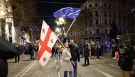 Anti-government protesters wave a Georgian (L) and European Union (R) flag during a demonstration against the Georgian government's postponement of European Union accession talks until 2028, outside the Parliament in central Tbilisi on December 12, 2024. Photo by Giorgi ARJEVANIDZE / AFP.