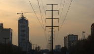 Traffic flows on a main road past electricity transmission towers in Tehran on December 16, 2024. Iran has suspended operations at several power plants over fuel shortages that have been intensified by rising demand during a spell of freezing weather. (Photo by ATTA KENARE / AFP)
