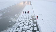 This aerial picture shows workers harvesting ice from the frozen Songhua river in preparation for the annual Harbin Ice and Snow World festival in Harbin, China's northeast Heilongjiang province on December 17, 2024. (Photo by Adek Berry / AFP)