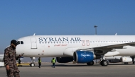 A fighter walks past as ground personnel prepare a Syrian Air aircraft for departure to the city of Aleppo, at the Damascus international airport on December 18, 2024. (Photo by Louai Beshara / AFP)