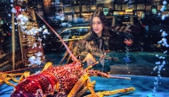 A woman looks at a giant lobster in a Chinese seafood restaurant's aquarium in Hong Kong on December 19, 2024. (Photo by Mladen ANTONOV / AFP)