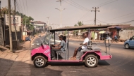 Self-thought innovator James Samba (L) drives an eco-friendly electric vehicle he made from scrap metals in Freetown on December 18, 2024. (Photo by Saidu Bah / AFP)