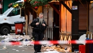 Debris a closed stalls are seen as a police officers stands on the site of a car-ramming attack on a Christmas market in Magdeburg, eastern Germany, on December 21, 2024. (Photo by John MACDOUGALL / AFP)