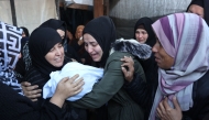 Palestinian women mourn a dead child, killed in an Israeli strike the previous night, at Al-Ahli Arab hospital, also known as the Baptist hospital, in Gaza City on December 21, 2024. (Photo by Omar Al-Qattaa / AFP)
 