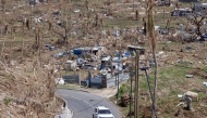 A car drives past destroyed homes in Pamandzi on the French Indian Ocean territory of Mayotte, after the cyclone Chido hit the archipelago on December 21, 2024. (Photo by PATRICK MEINHARDT / AFP)
