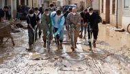 File: People with masks and soldier remove mud in a flooded street on November 6, 2024, in Catarroja, in the region of Valencia, eastern Spain, in the aftermath of deadly floods. (Photo by Cesar Manso / AFP)