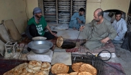 Afghan baker Jamil Ghafori (L) preparing traditional flatbreads locally known as Naan, at a bakery in Kabul. (Photo by Wakil Kohsar / AFP)