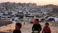 Children sit together overlooking a view of tents sheltering Palestinians displaced by confict by the Hamad Residential City complex in the north of Khan Yunis in the southern Gaza Strip on December 22, 2024. Photo by BASHAR TALEB / AFP