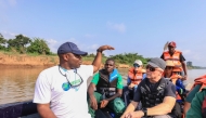 Aristide Takoukam Kamla (L), a marine biologist, researcher and conservationist specialising in the African manatee, talks to tourists and other biologists on a boat in Dizangue, on December 10, 2024. (Photo by Daniel Beloumou Olomo / AFP)