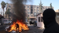 A man watches a pile of illicit drugs burn, as Syria's new authorities burn drugs reportedly seized from a security branch, in Damascus on December 25, 2024. (Photo by Omar Haj Kadour / AFP)