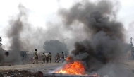 Pedestrians walk past a burning barricade in Maputo on December 24, 2024. (Photo by Amilton Neves / AFP)
