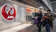 People walk past a check-in counter for Japan Airlines at the departures hall of Haneda Airport in Tokyo on December 26, 2024. (Photo by Yuichi YAMAZAKI / AFP)