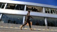 A member of Yemen's security forces walks past a damaged building at Sanaa international airport on December 27, 2024, following Israeli strikes at the site the previous day. (Photo by Mohammed Huwais / AFP)