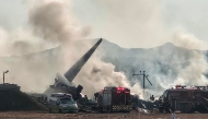 Smoke rises from the tail section of a Jeju Air Boeing 737-800 series aircraft after the plane crashed and burst into flames at Muan International Airport in South Jeolla Province, some 288 kilometres southwest of Seoul on December 29, 2024. (Photo by YONHAP / AFP) 