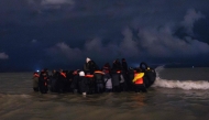 (Files) Migrants board a smuggler's inflatable dinghy in an attempt to cross the English Channel, on Bleriot beach at Sangatte, near Calais, northern France on October 30, 2024. (Photo by Sameer Al-Doumy / AFP)