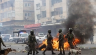 (FILES) Anti-riot police officers with their dogs walk down Eduardo Mondlane Avenue past burning barricades made by protesters in Maputo November 7, 2024. (Photo by ALFREDO ZUNIGA / AFP)
