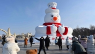 This picture taken on December 17, 2024 shows people having picture with a snowman sculpture in Harbin, China’s Northeastern Heilongjiang province. (Photo by Adek Berry / AFP) 