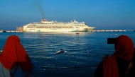 Women take pictures of a cruise ship docked in the Old Doha Port on December 26, 2024. (Photo by KARIM JAAFAR / AFP) 