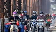 Motorists wearing face masks ride scooters along Long Bien Bridge amid heavy air pollution in Hanoi on January 3, 2025. Photo by Nhac NGUYEN / AFP