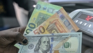 File: A teller displays US dollars and Euros at a money exchange market / AFP