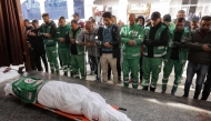 Palestinian Red Crescent paramedics pray by the body of their fallen colleague Mahmud al-Muhadad, who was reportedly killed in an Israeli air strike in Jabalia in the northern Gaza Strip, as it lies at the Ahli Arab hospital, also known as the Baptist hospital, in Gaza City on January 4, 2025. (Photo by Omar AL-QATTAA / AFP)
