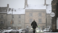 A pedestrian carries a milk bottle across the covered in snow streets of Stow-on-the-Wold, central England, on January 5, 2025 as heavy snow across parts of England are set to cause disruption. Photo by JUSTIN TALLIS / AFP