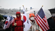 Supporters of impeached South Korea president Yoon Suk Yeol hold US and South Korean flags as they take part in a rally near his residence as snow falls in Seoul on January 5, 2025. (Photo by Philip FONG / AFP)
