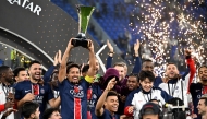 Paris Saint-Germain players celebrate with the trophy after winning the French Champions' Trophy (Trophee des Champions) final football match between Paris Saint-Germain (PSG) and AS Monaco (ASM) at the Stadium 974 in Doha on January 5, 2025. (Photo by Mahmud HAMS / AFP)