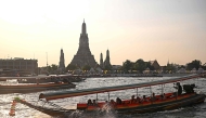 Tourists ride a longtail boat past Wat Arun temple along the Chao Praya river in Bangkok on December 19, 2024. Photo by Lillian SUWANRUMPHA / AFP