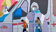 Pedestrians walk past a wall mural promoting awareness on using face masks, in Bengaluru on January 6, 2025. Photo by Idrees MOHAMMED / AFP