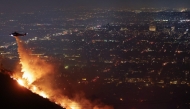 A firefighting helicopter drops water as the Sunset Fire burns in the Hollywood Hills with evacuations ordered on January 8, 2025 in Los Angeles, California. Mario Tama/Getty Images/AFP