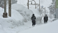 Pedestrians walk past high drifts of snow along a street in the northern Japanese city of Aomori on January 9, 2025. (Photo by JIJI Press / AFP) / Japan OUT