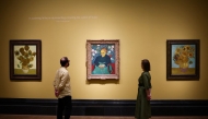 Visitors look at (from L) three paintings made by late Dutch artist Vincent Van Gogh 